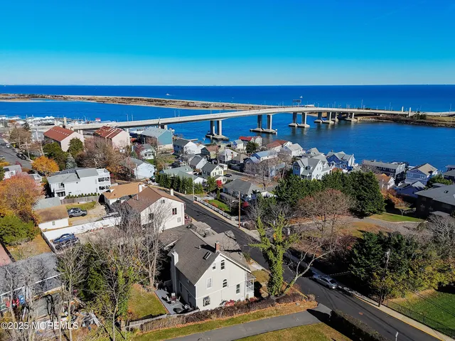 an aerial view of ocean and residential houses with outdoor space
