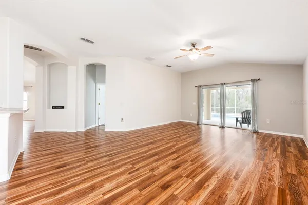 a view of empty room with wooden floor and fan