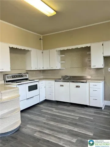 a kitchen with granite countertop a stove cabinets and wooden floor