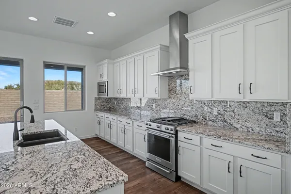 a kitchen with granite countertop white cabinets and stainless steel appliances