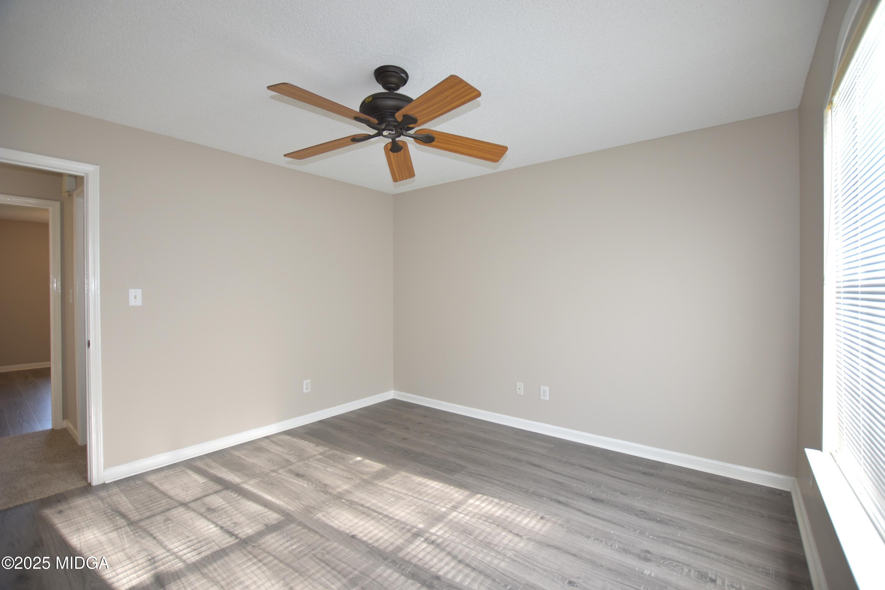 6550 Skipper Road Macon, GA 31216 - Photo 16 of 35 an empty room with wooden floor a ceiling fan and windows