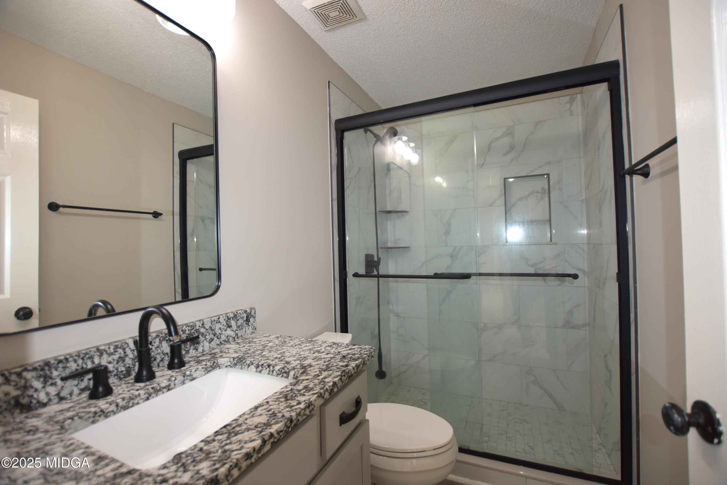 6550 Skipper Road Macon, GA 31216 - Photo 17 of 35 a bathroom with a granite countertop shower sink vanity and toilet