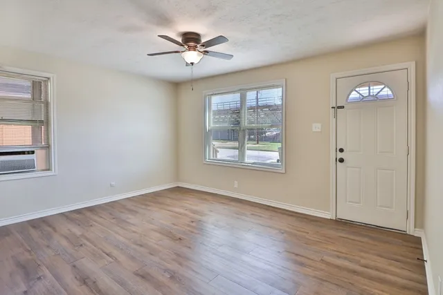 a view of an empty room with a window and wooden floor
