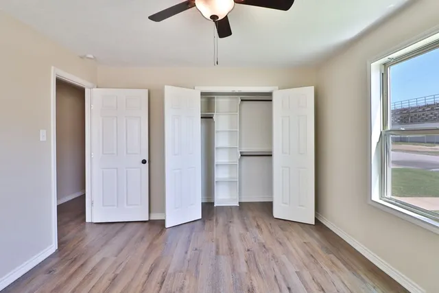 a view of an empty room with a window and wooden floor