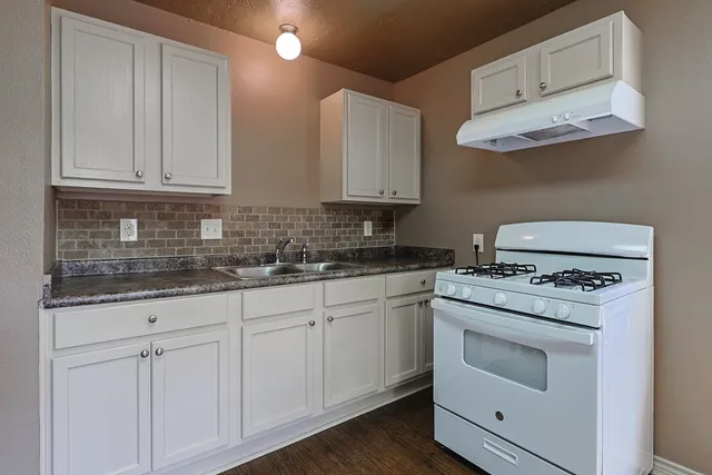 a kitchen with granite countertop white cabinets and white appliances