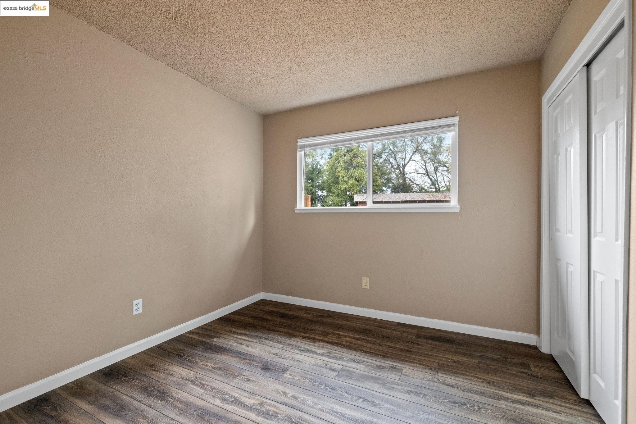 17943 Plateau Road Sonora, CA 95370 - Photo 7 of 11 Unfurnished bedroom with a closet, dark wood finished floors, and a textured ceiling