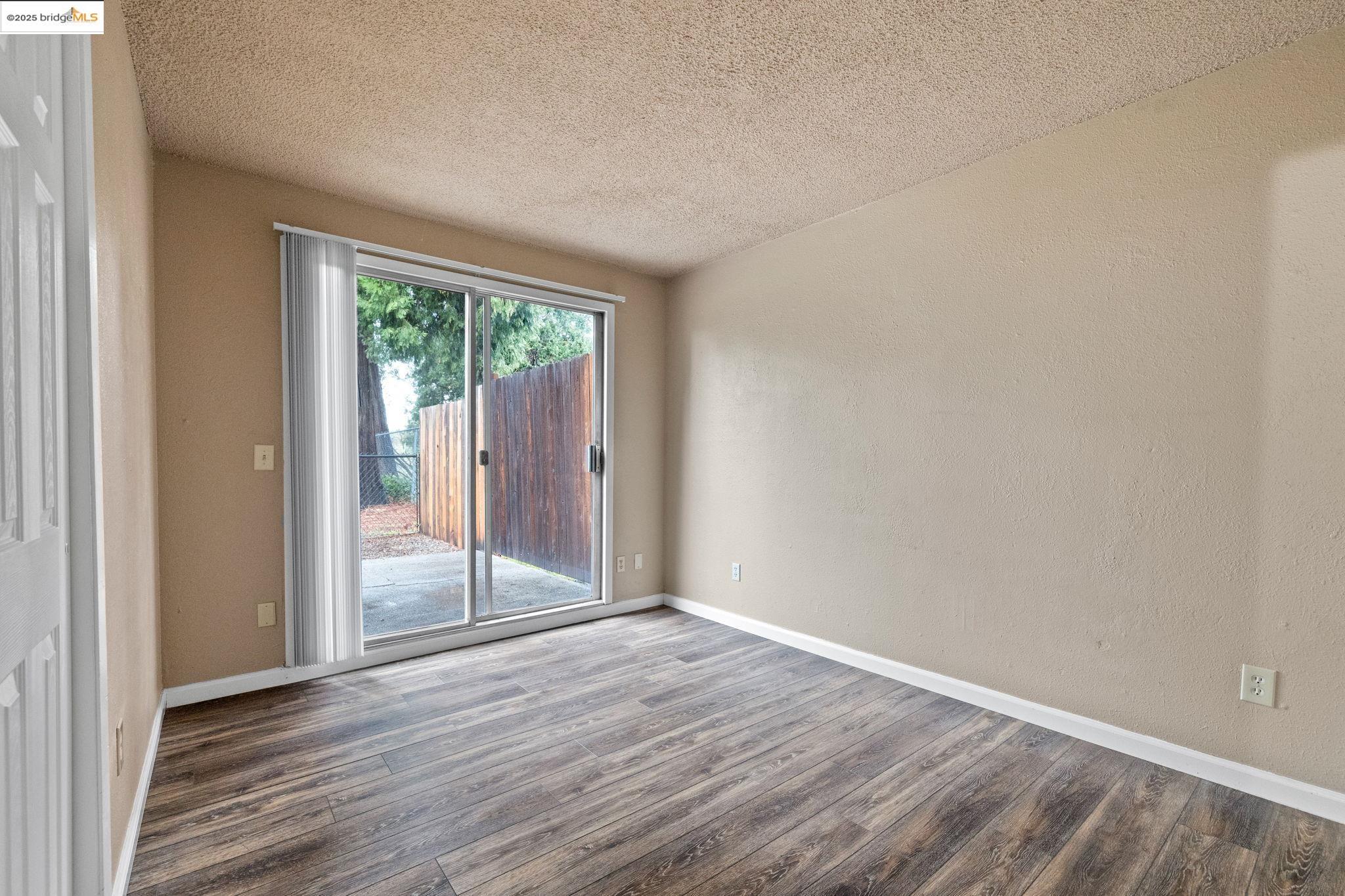 17943 Plateau Road Sonora, CA 95370 - Photo 8 of 11 Empty room featuring wood finished floors, a textured ceiling, and a textured wall