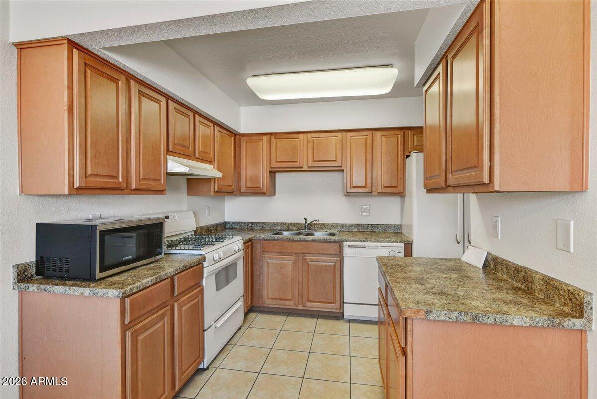 303 North Miller Road, Unit 2002 Scottsdale, AZ 85257 - Photo 4 of 12 a kitchen with stainless steel appliances granite countertop wooden cabinets a stove a sink and dishwasher