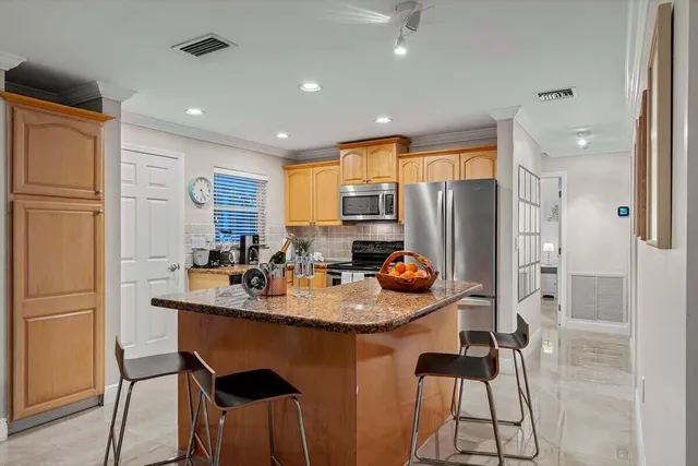 a kitchen with stainless steel appliances granite countertop a refrigerator a sink a stove a dining table and chairs