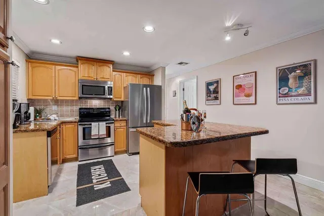 a kitchen with stainless steel appliances a sink a stove a refrigerator cabinets and a dining table