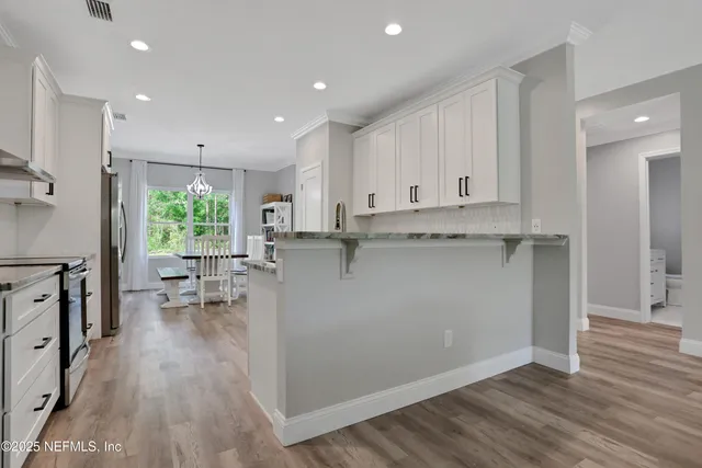 a kitchen with white cabinets a sink dishwasher and a stove with wooden floor