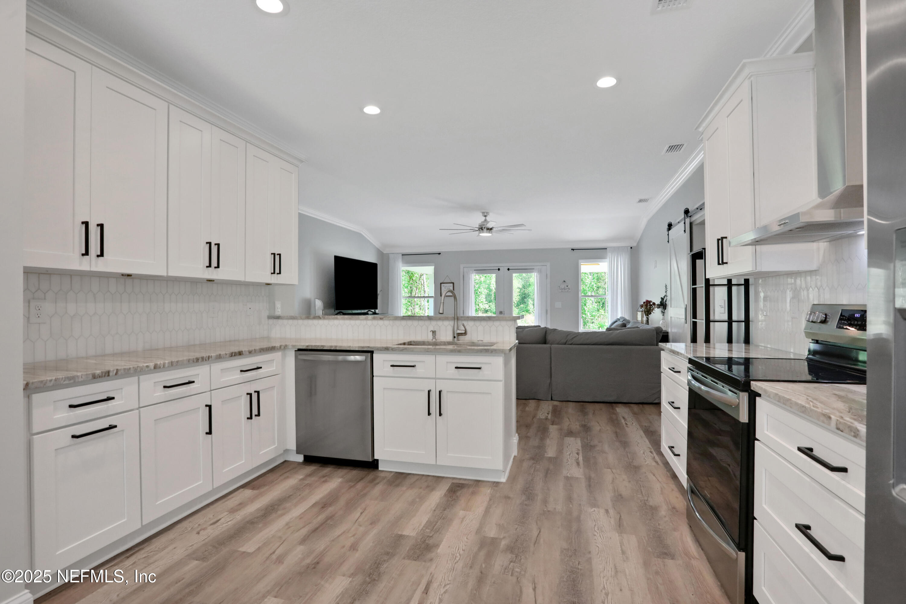 4467 Monroe Smith Road Jacksonville, FL 32210 - Photo 25 of 61 a kitchen with white cabinets a sink dishwasher and a stove with wooden floor