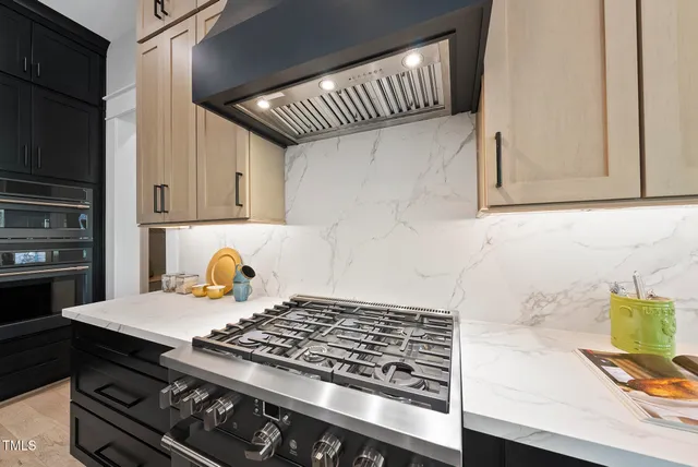 a kitchen with stainless steel appliances kitchen island granite countertop a sink a stove and a refrigerator