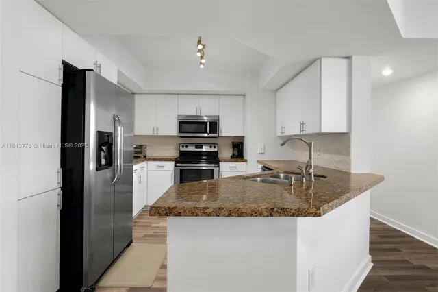 a kitchen with kitchen island granite countertop a sink stove and refrigerator