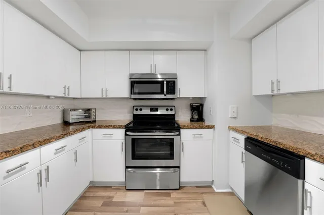 a kitchen with granite countertop white cabinets and stainless steel appliances