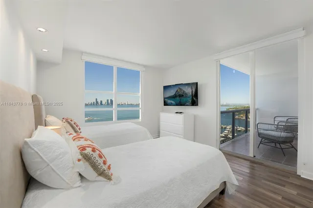 a bedroom with a bed and a flat tv screen on dresser