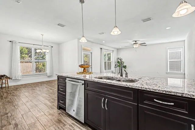 a kitchen with stainless steel appliances granite countertop a sink a stove and a wooden floors