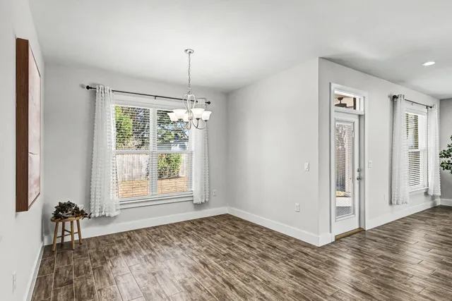 a view of an empty room with window and wooden floor