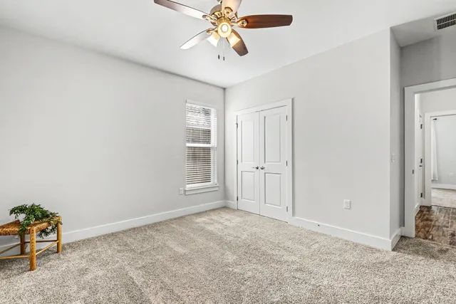 a view of an empty room with chandelier fan and closet area