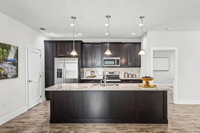 a large kitchen with granite countertop a sink a counter top space and cabinets