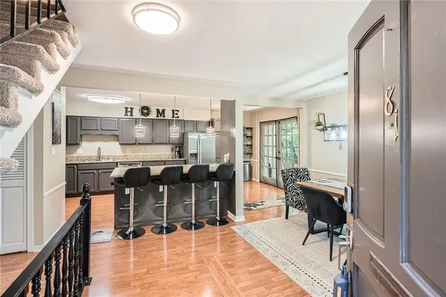 a dining hall with stainless steel appliances kitchen island granite countertop a table chairs and a living room view