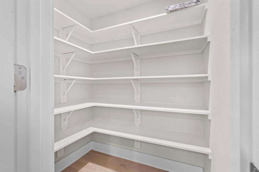2827 Manor Road, Unit 2201 Austin, TX 78722 - Photo 18 of 40 Spacious pantry with multiple white built-in shelves, white walls, and wood-finish flooring