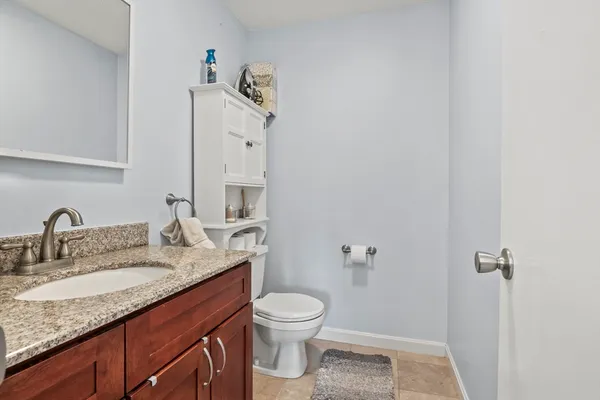 a bathroom with a granite countertop sink a toilet and a mirror