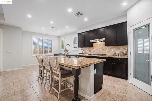 a kitchen with stainless steel appliances a dining table chairs and refrigerator