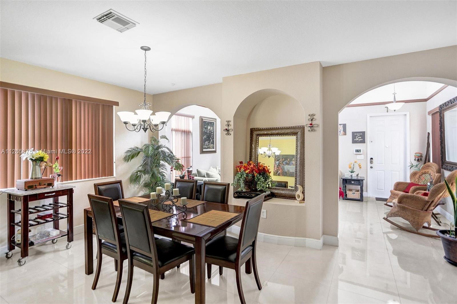 27846 Southwest 142nd Avenue Homestead, FL 33032 - Photo 11 of 56 a view of a dining room and livingroom with furniture wooden floor a chandelier
