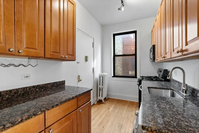 a kitchen with granite countertop cabinets stainless steel appliances a sink and a window