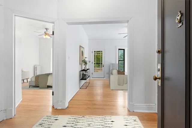 a view of a hallway with wooden floor and a living room