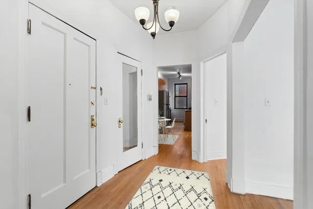 a view of a hallway with wooden floor and a bathroom