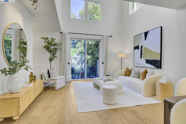 a living room with furniture large window and potted plants
