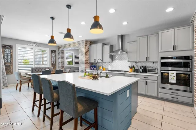 a kitchen with stainless steel appliances granite countertop a stove a sink a oven a dining table and chairs with wooden floor