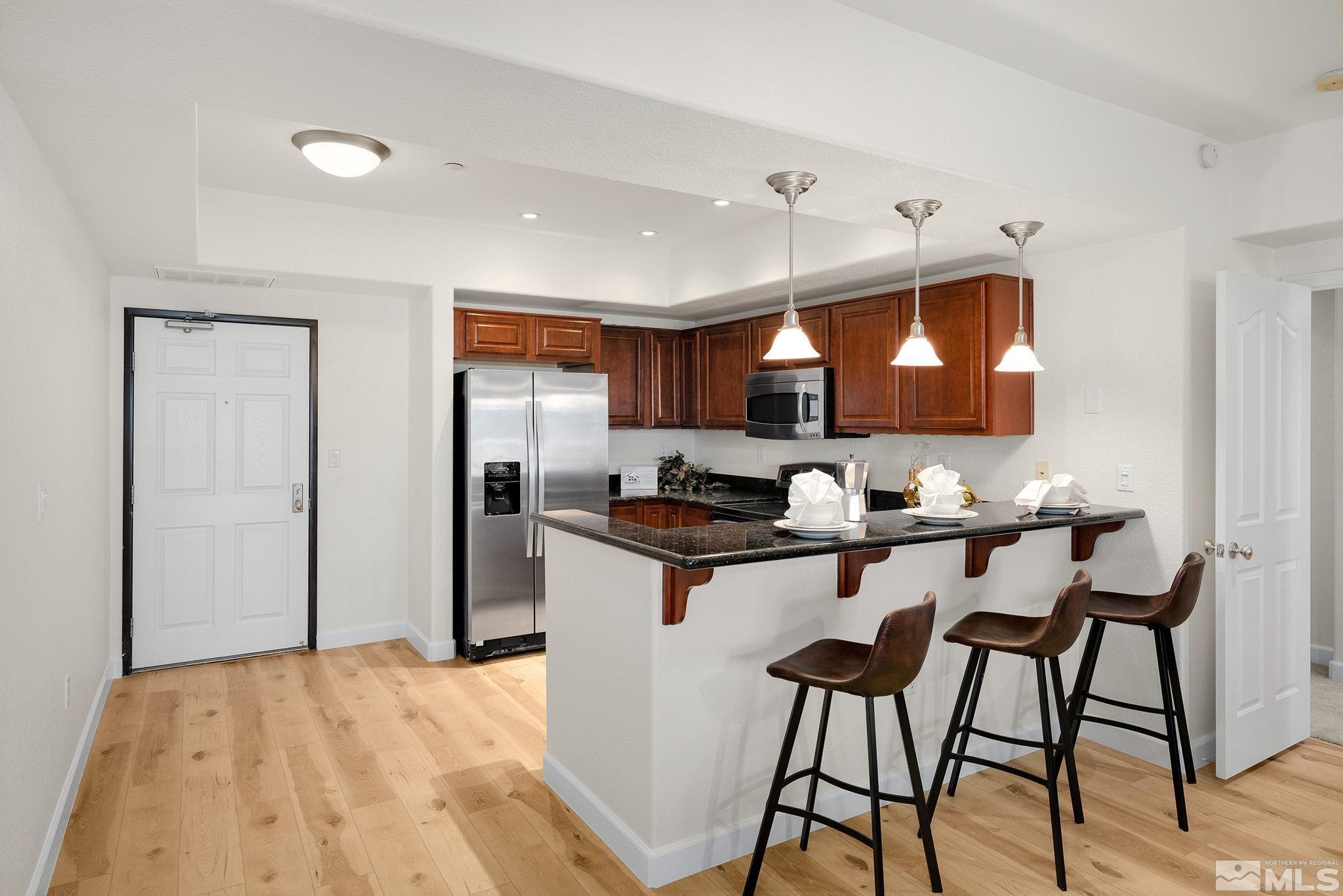 200 West 2nd Street, Unit 1503 Reno, NV 89501 - Photo 6 of 28 a kitchen with stainless steel appliances kitchen island a table chairs in it and wooden floors