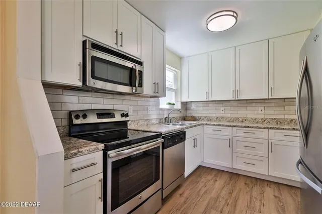 a kitchen with granite countertop cabinets stainless steel appliances and wooden floor