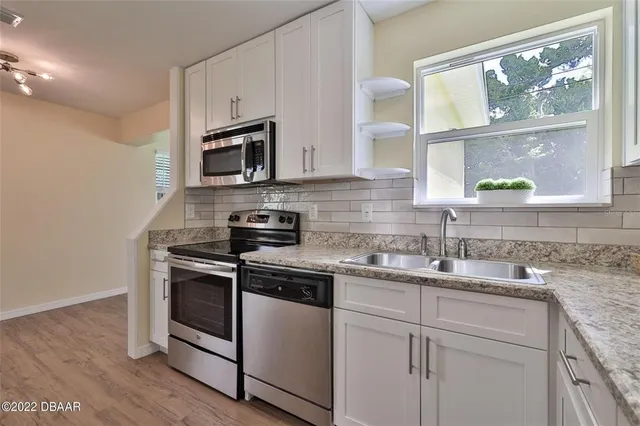 a kitchen with stainless steel appliances granite countertop white cabinets a stove a microwave and a window