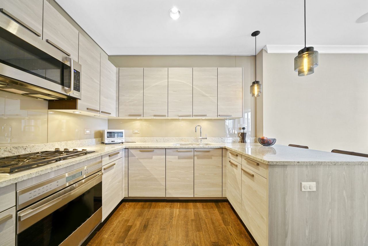 10 East Delaware Place, Unit 18E Chicago, IL 60611 - Photo 11 of 56 a kitchen with stainless steel appliances a sink dishwasher stove and white cabinets with wooden floor