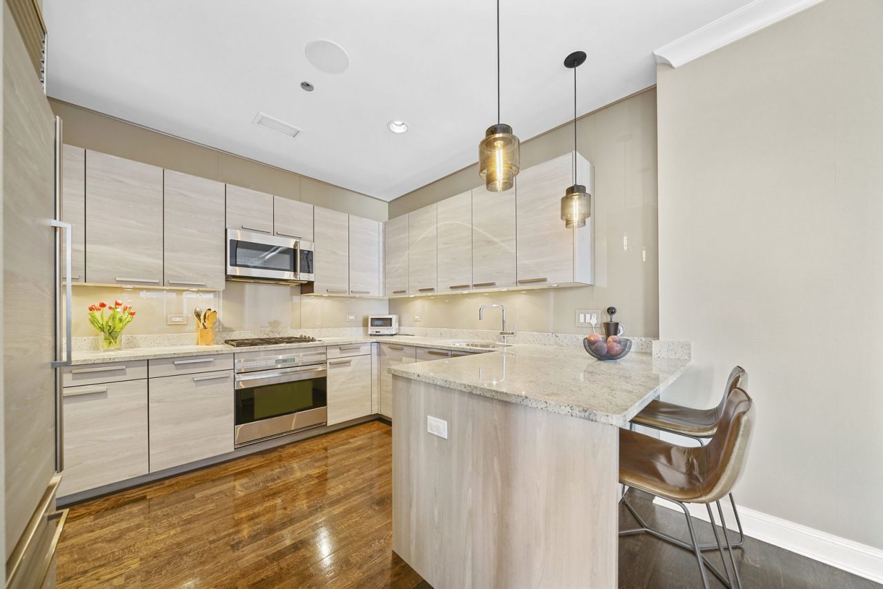 10 East Delaware Place, Unit 18E Chicago, IL 60611 - Photo 13 of 56 a kitchen with stainless steel appliances granite countertop a stove a sink dishwasher and a refrigerator with wooden floor