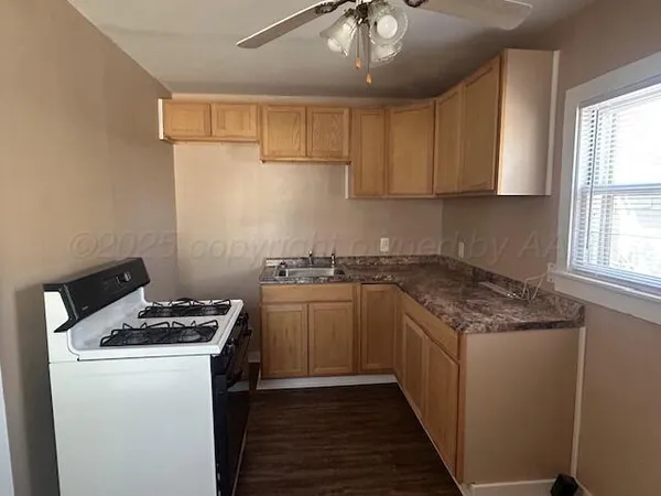 a kitchen with granite countertop a sink a stove and cabinets