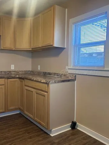 a kitchen with granite countertop wooden cabinets and a hard wood floor