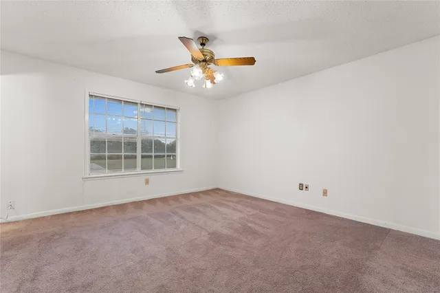 an empty room with windows and fan