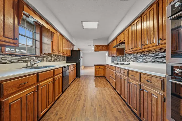 a view of kitchen with stainless steel appliances wooden floor and a large window