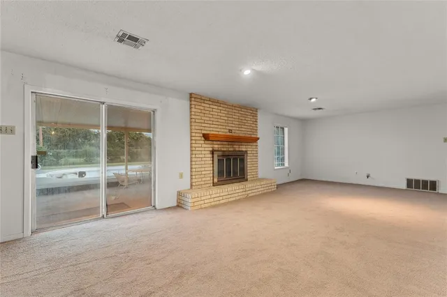 an empty room with a fireplace and large window