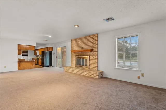 a view of an empty room with a window and kitchen view