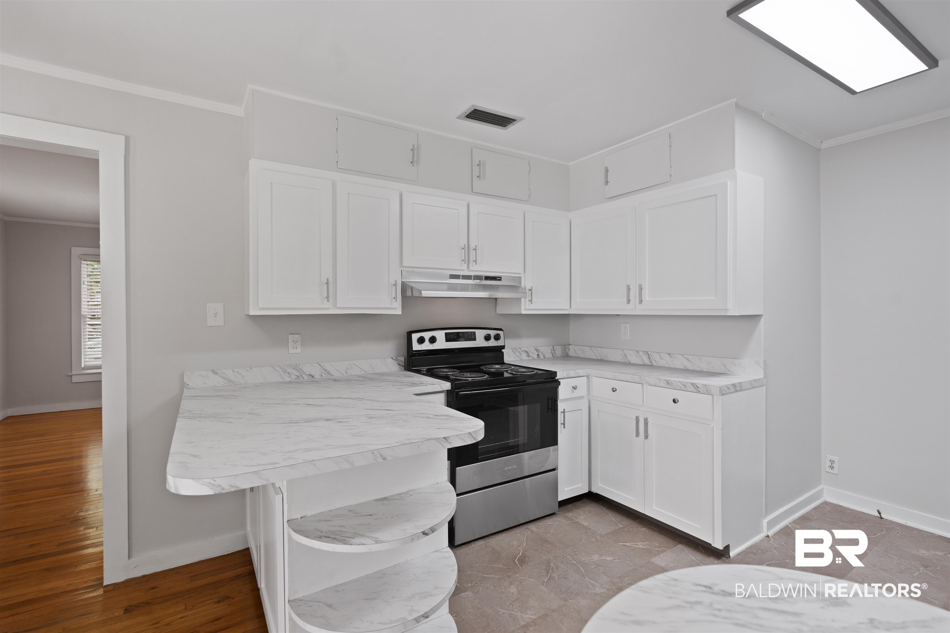 2126 Barron Place Mobile, AL 36605 - Photo 13 of 33 Kitchen with a kitchen breakfast bar, stainless steel range with electric cooktop, light hardwood / wood-style flooring, white cabinetry, and kitchen peninsula