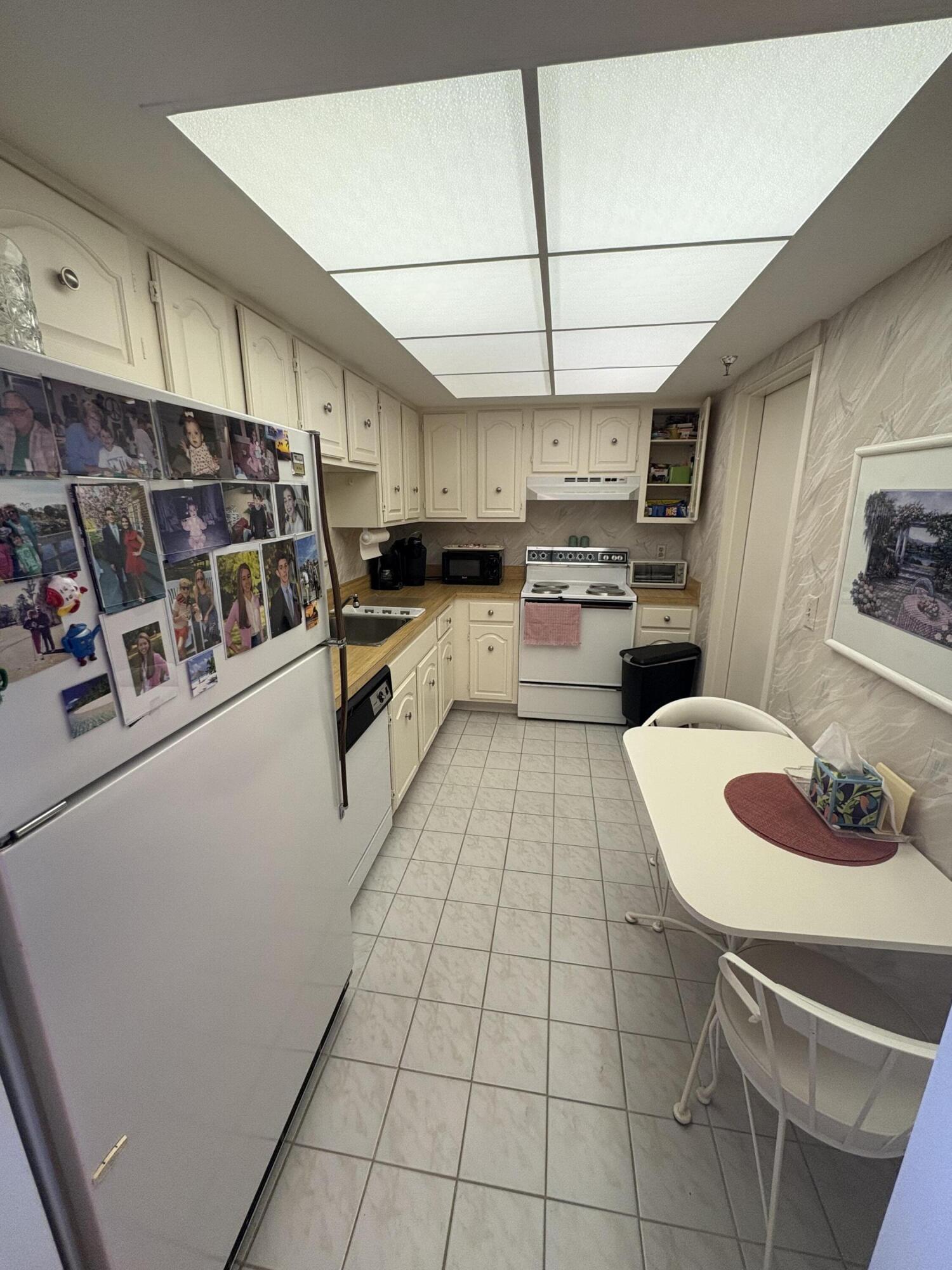 6895 Willow Wood Drive, Unit 1083 Boca Raton, FL 33434 - Photo 6 of 56 a kitchen with stainless steel appliances a sink a stove a refrigerator cabinets and dining table