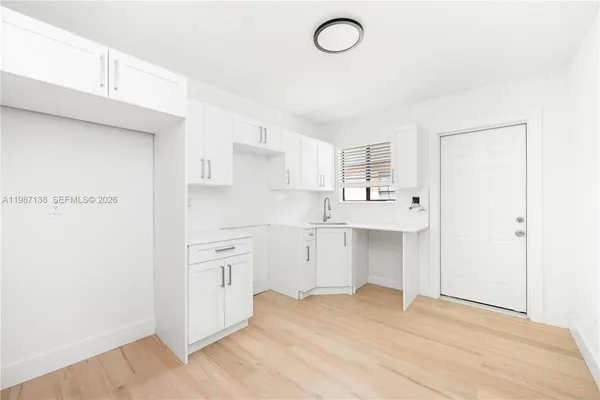 a kitchen with white cabinets and sink
