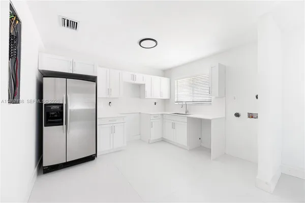 a kitchen with white cabinets and refrigerator