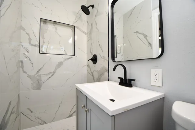 a bathroom with a sink and mirror with toilet